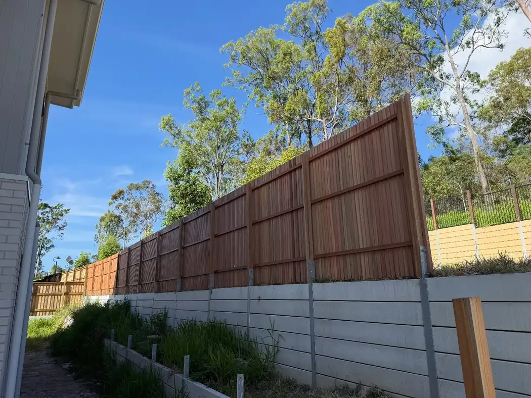 Hardwood fence panels stepped along the top of a concrete retaining wall